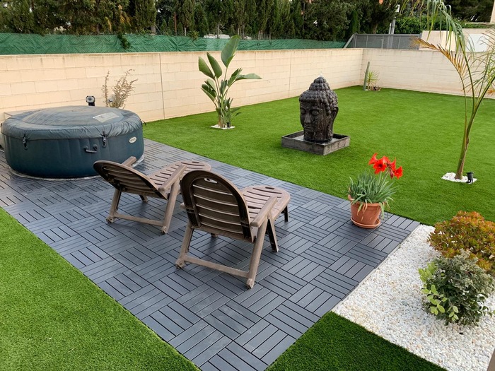 Zona de relax con césped artificial y decoración en jardín privado